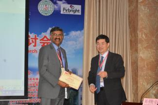 Two people in front of a banner. One is holding a certificate